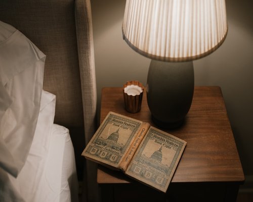 Open book under a warm reading lamp on a nightstand